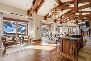 Kitchen featuring open floor plan, dark stone counters, a glass covered fireplace, and high vaulted ceiling