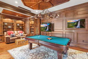 Game room with ornamental molding, built in shelves, pool table, wood ceiling, and wood-type flooring
