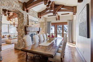 Dining space with hardwood / wood-style floors, a fireplace, a chandelier, and beamed ceiling