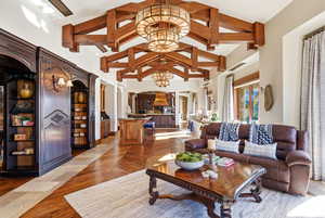 Living area with arched walkways, a chandelier, high vaulted ceiling, and light wood-style floors