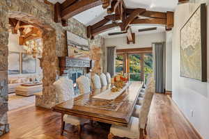 Dining room with a stone fireplace, a chandelier, and wood-type flooring