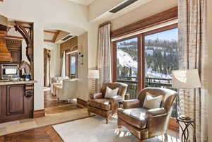 Sitting room with arched walkways, healthy amount of natural light, inlaid floor details, and stone tile flooring