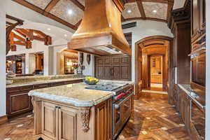 Kitchen with stainless steel appliances, island range hood, recessed lighting, light stone countertops, and a center island