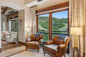 Sitting room featuring arched walkways, a forest view, and inlaid floor details