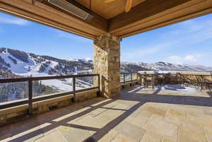 Snow covered patio featuring a patio, a mountain view, and a ceiling fan