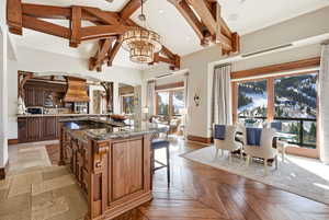 Kitchen with dark stone counters, arched walkways, hanging light fixtures, a breakfast bar, and high vaulted ceiling