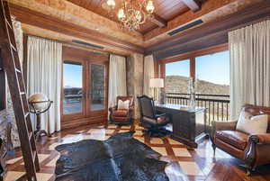 Sitting room with a wooden ceiling with exposed beams, a chandelier, a desk, and inlaid floor details