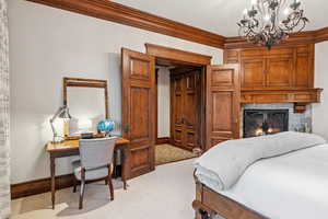 Bedroom with ornamental molding, light carpet, a fireplace, and a chandelier
