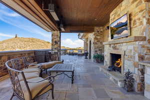 View of patio with an outdoor stone fireplace