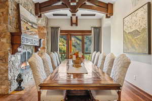 Dining space featuring a fireplace, wood-type flooring, and beamed ceiling