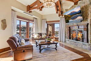 Living room featuring healthy amount of natural light, beamed ceiling, high vaulted ceiling, wood-type flooring, and a fireplace