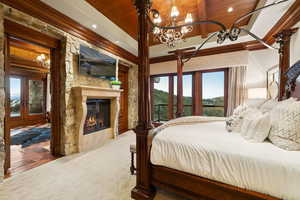 Bedroom featuring a wood ceiling with exposed beams, a chandelier, recessed lighting, a glass covered fireplace, and crown molding