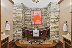 Full bath featuring a soaking tub and wood-type flooring