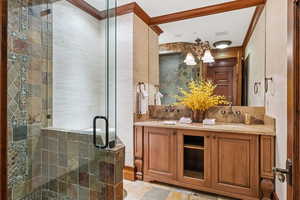 Bathroom featuring double vanity, a shower stall, and crown molding