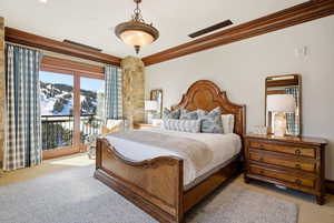 Carpeted bedroom with crown molding and access to exterior