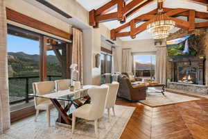 Dining area featuring a mountain view, high vaulted ceiling, beamed ceiling, a stone fireplace, and a chandelier