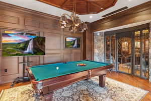 Recreation room with wood finished floors, pool table, a decorative wall, wooden ceiling, and crown molding