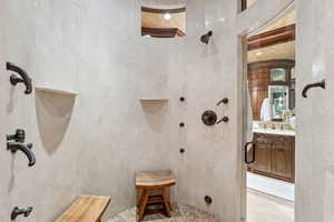 Bathroom with tiled shower, vanity, and inlaid floor details