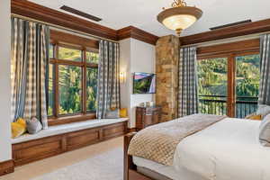 Carpeted bedroom with multiple windows, crown molding, and access to outside
