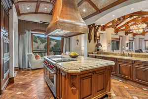 Kitchen with open floor plan, appliances with stainless steel finishes, island range hood, recessed lighting, and light stone counters