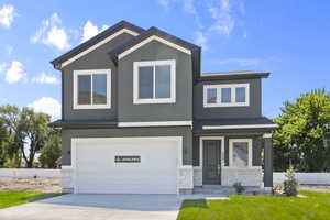 View of front of property featuring stone siding, stucco siding, an attached garage, and concrete driveway