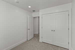 Unfurnished bedroom with light carpet, a closet, and recessed lighting
