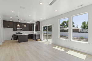 Kitchen with a center island, light wood-style floors, light countertops, dark brown cabinets, and recessed lighting