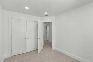 Unfurnished bedroom featuring light colored carpet, a closet, and recessed lighting
