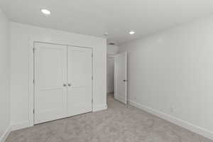 Unfurnished bedroom with carpet, a closet, and recessed lighting