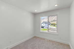 Empty room featuring light carpet, a textured ceiling, and recessed lighting
