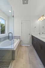 Bathroom with double vanity, a bath, tile patterned flooring, and a stall shower