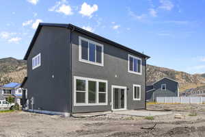 Back of house with a mountain view, stucco siding, and a patio