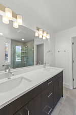 Bathroom featuring double vanity, tile patterned flooring, and a shower stall