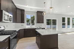 Kitchen featuring stainless steel appliances, light countertops, light wood-style flooring, recessed lighting, and a kitchen island