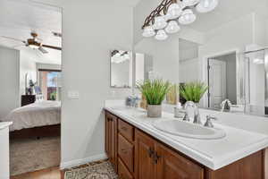 Ensuite bathroom featuring double vanity, ceiling fan, and wood finished floors