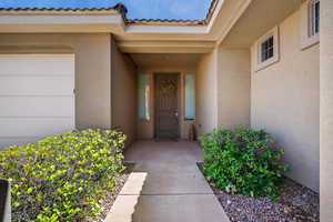 Doorway to property featuring stucco siding, an attached garage, and a tiled roof