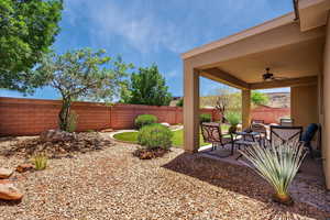Fenced backyard featuring a ceiling fan and a patio area