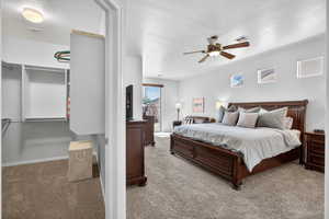 Bedroom with a textured ceiling, light carpet, and ceiling fan