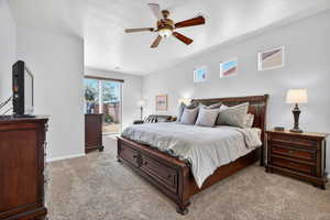 Bedroom featuring access to outside, light colored carpet, a textured ceiling, and a ceiling fan