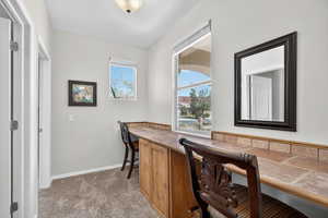 Carpeted office space featuring built in desk and baseboards