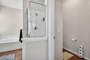 Bathroom featuring wood finished floors, a bath, and a stall shower