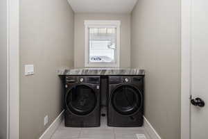 Laundry area featuring washing machine and clothes dryer and tile patterned flooring
