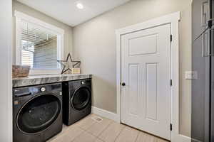 Laundry room with independent washer and dryer, light tile patterned floors, and recessed lighting