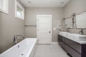 Bathroom with a freestanding bath, double vanity, and recessed lighting