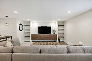 Living room with recessed lighting, wood finished floors, and built in features