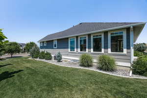 View of property exterior with a lawn and roof with shingles