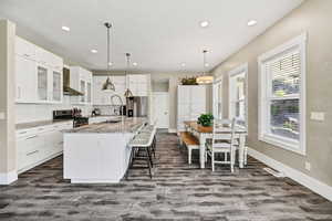 Kitchen with pendant lighting, glass insert cabinets, white cabinets, a breakfast bar area, and recessed lighting