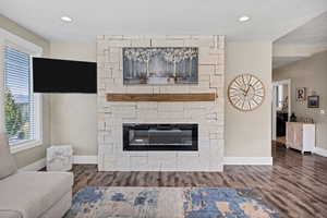 Living area with a fireplace, dark wood-type flooring, and recessed lighting