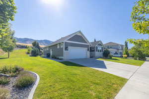 View of front of home featuring a front lawn, driveway, a garage, and stone siding
