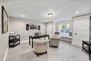 Home office with light colored carpet and recessed lighting